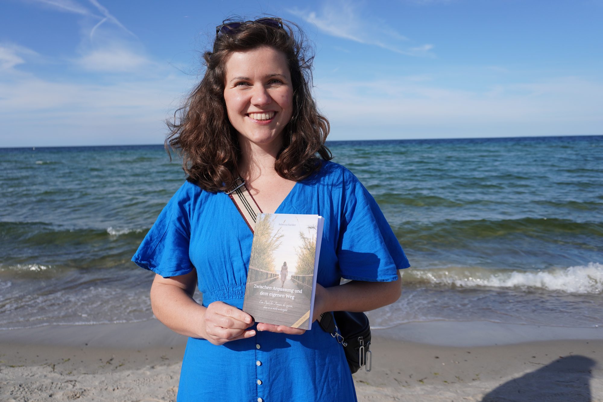 Rebecca Fackler mit ihrem Buch am Ostseestrand