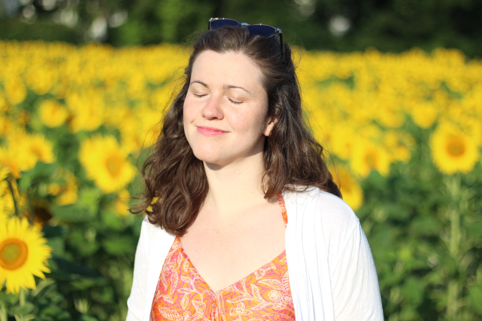 Rebecca Fackler vor einem Sonnenblumenfeld, die Augen geschlossen, lächelnd