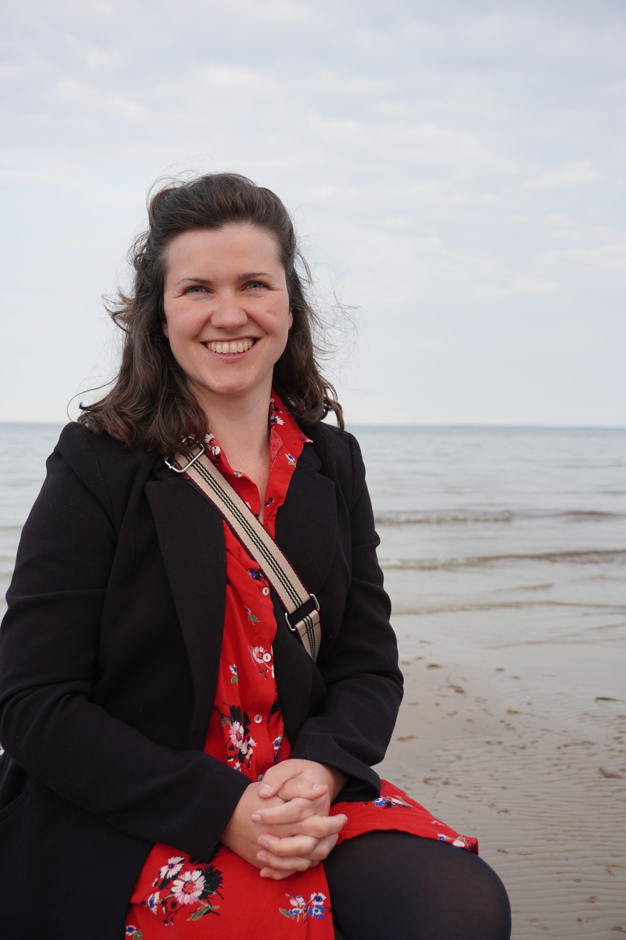 Rebecca Fackler am Ostseestrand, sitzend, mit Blick in die Kamera